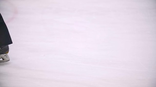 Hockey players drive through a hockey field with a black puck. View of legs. Slow motion