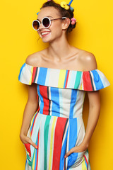 Fashion cool girl posing in sunglasses on yellow background.
