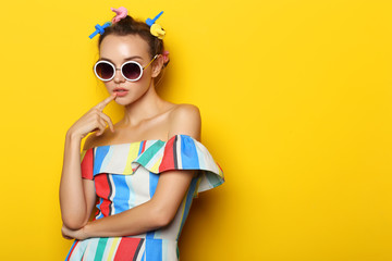Fashion cool girl posing in sunglasses on yellow background.
