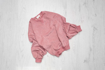 Pink sweater on wooden background