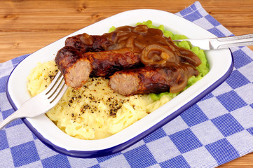 Sausages and mashed potato meal with mushy peas and onion gravy