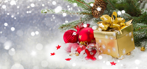 fir tree and red christmas decorations and gift box on snow , winter banner