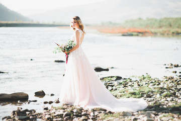Fototapeta na wymiar Portrait of stunning bride with long hair posing with great bouquet near river