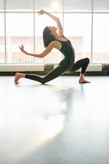 Full length portrait of contemporary young woman dancing passionately in studio hall lit by serene sunlight, copy space © Seventyfour