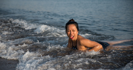 woman laying in waves in Greece and laughing