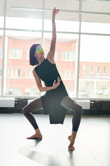 Full length portrait of contemporary young woman dancing alone in studio lit by serene sunlight © Seventyfour