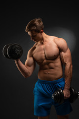 Fototapeta na wymiar Strong bodybuilder with perfect deltoid muscles, shoulders, biceps, triceps and chest. Close up power fitness man. Handsome power athletic man in training swap muscles with dumbbells. Black background