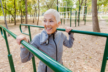Obraz premium Smiling Mature Woman Exercise At Outdoor Gym