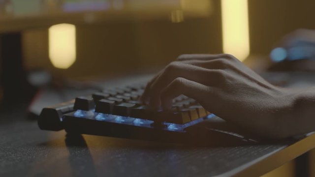 Video gamer or hacker. Hands on computer keyboard and mouse with RGB backlight. Close-up dolly panning. Shallow depth of field