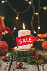christmas candle with red sale tag on wooden stump