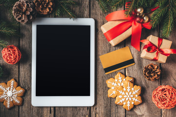 flat lay with digital tablet, credit card, cookies and christmas gifts on wooden background