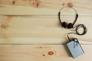 Old portable cassette tape player and headphones on wooden floor