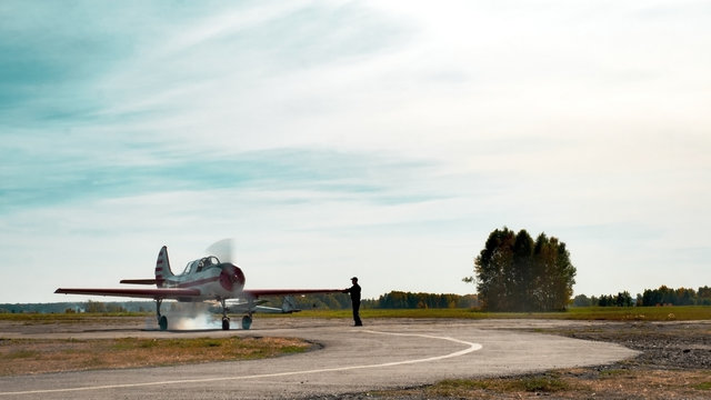 View of airplane on grassy airfield close up; classic plane taxiing to takeoff on runway; training aerobatic flight of oldschool aircraft; leisure activity and entertainment for visitors and tourists