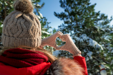 Female Hands Making Finger Shape Of A Heart Sign in winter snowy forest