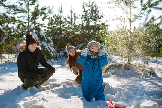 Father, mother and son play in snow in winter park. Happy winter holiday