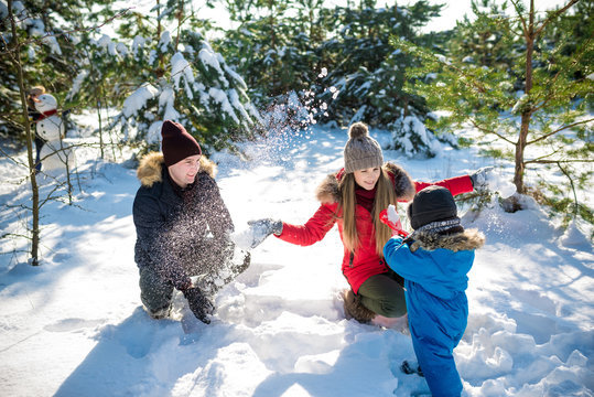 Father, mother and son play in snow in needles wood. Happy wintertima