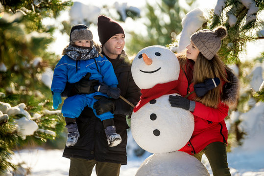 Happy family with snowman in winter park