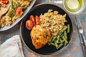 Grilled chicken thighs with bulgur, asparagus beans and tomatoes. Delicious lunch. Copy space.