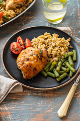 Grilled chicken thighs with bulgur, asparagus beans and tomatoes. Delicious lunch. Copy space.