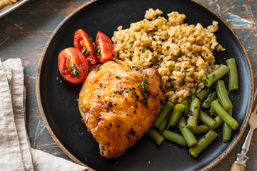 Grilled chicken thighs with bulgur, asparagus beans and tomatoes. Delicious lunch. Copy space.