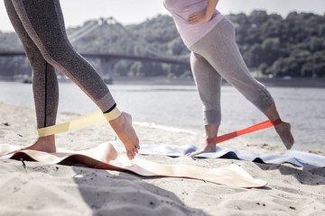 Female sport. Close up of female legs in rubber band during the sports training