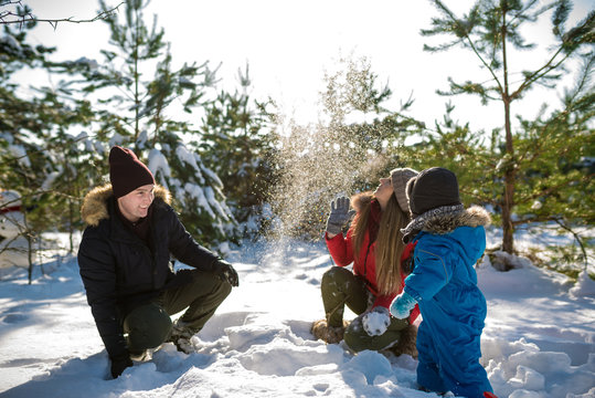 Father, mother and son play in snow in needles wood. Happy wintertima