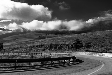 wind turbine and road on a black and withe cloudy sky