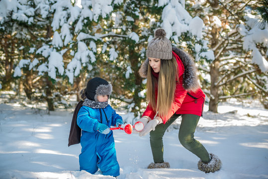 Happy young mother and her son have fun in winter. Play in snow