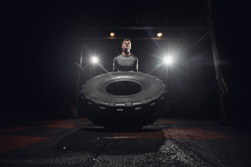 Muscular fitness man moving large tire in gym center, concept lifting, workout training