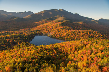 Morning light illuminates the fall color in the Adirondack Mountains over Heart Lake