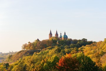 Fototapeta premium Cathedral towers amidst autumnal trees, Tumskie Hill in Plock, Poland