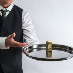 Butler / waiter holds a silver tray with a ten dollar bill. Concept for tip and money exchange. White background.