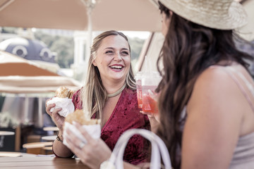 In the cafe. Joyful positive women talking to each other while sitting in the cafe