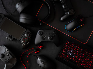 gamer workspace concept, top view a gaming gear, mouse, keyboard, joystick, headset, mobile joystick, in ear headphone and mouse pad on black table background. © ekkaphan