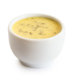Creamy herb dressing in white ceramic condiment bowl isolated on white.