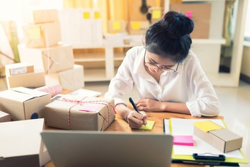 Asian woman working on laptop at home are arrange delivery packaging