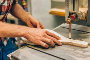 close up of the hands of a worker while sawing wood