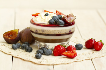Italian dessert - panna cotta with berries and berry jelly. Homemade berries aspic with different layers of chocolate, milk, cream, berry with fresh strawberries, fig and blueberries