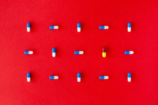 Graphic colourful pill composition on a solid red background