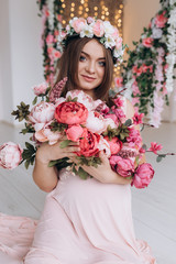 Beautiful pregnant woman in pink dress poses with colorful red bouquet