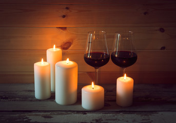 Fototapeta na wymiar Glasses of red wine with candles on wooden background