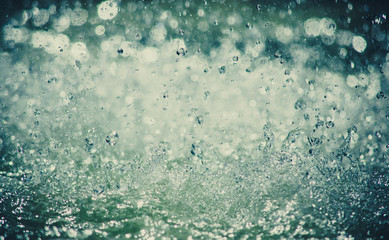 Many water drops splashing closeup. Cold blue colors and vignette on the edges. Fountain 