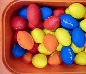 Fototapeta na wymiar Colorful rubber rugby balls in orange bucket.