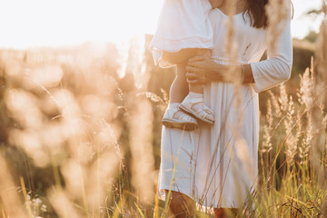 Beautiful portrait of charming mother and lovely little daughter walking across the field in the...