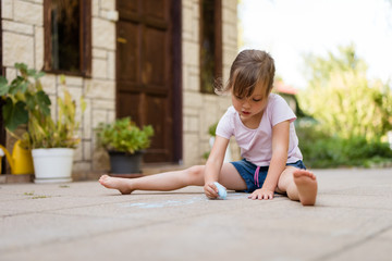 Creativity - girl drawing with chalk outdoors