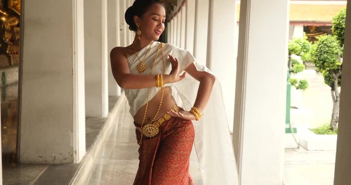 beautiful asian woman in thai traditional dress dancing traditional thai dance in Thai buddhist temple in bangkok wat suthat. outdoor next to temple