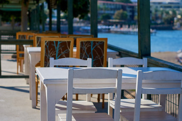 Cafe on the public beach. Wooden white table and chairs. The coast of the Aegean Sea. Turgusreis, Bodrum, Turkey