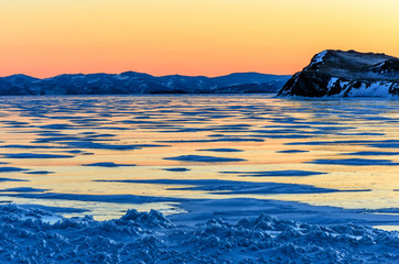 Naklejka premium View of the ice and the rising sun over the mountains, lake Baikal