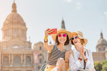 Two young happy women tourists friends hugging against the background of the National Museum of Art...