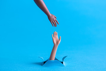 Two plastic hands on pastel blue background support abstract concept.